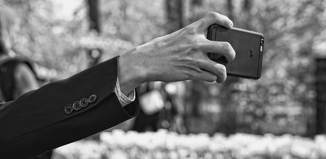 Extended arm with hand straining to hold a phone. Black and white image