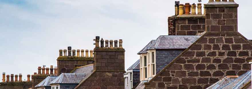 Chimneys and upstairs windows of brick terraced houses